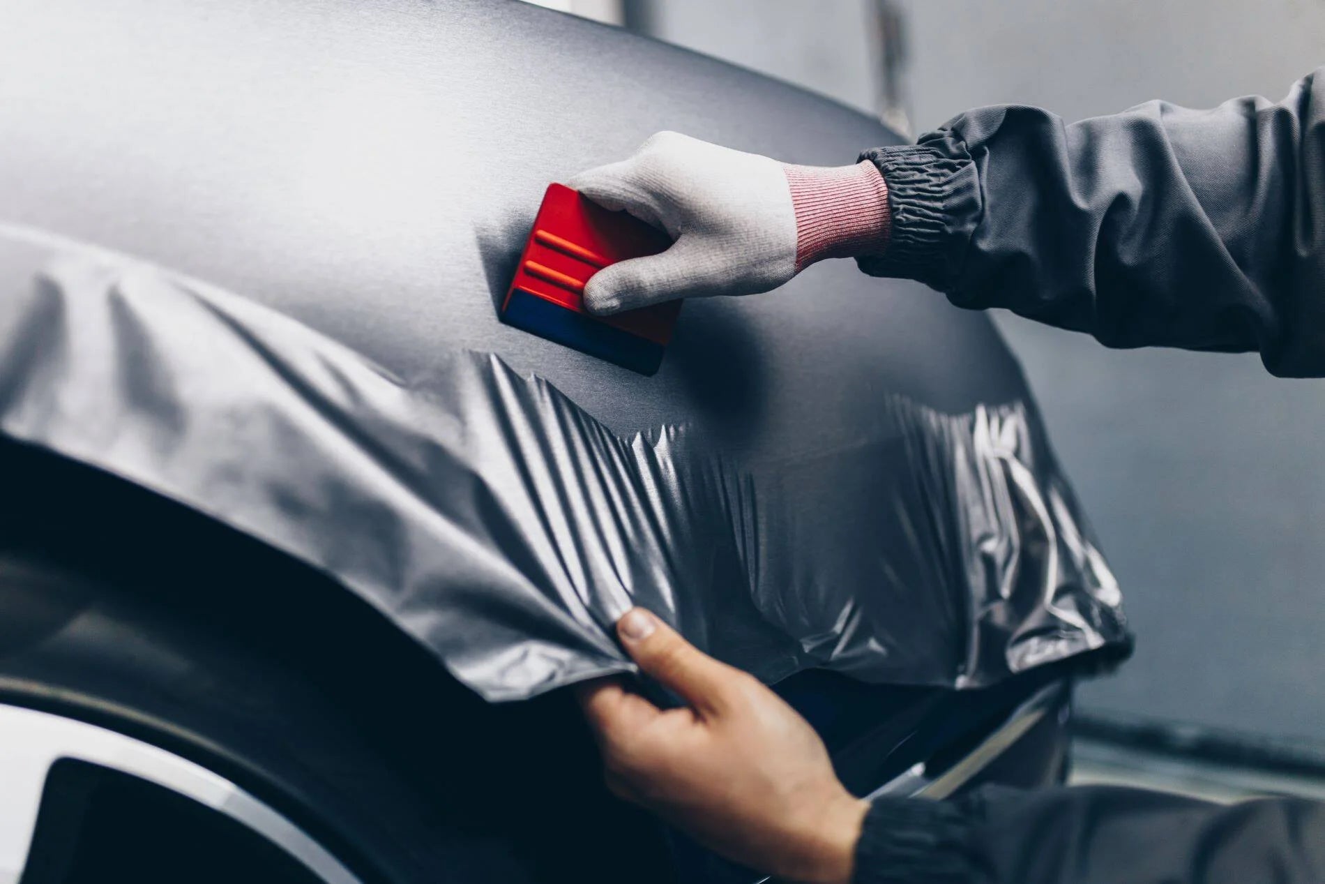 Person applying car wrap to a vehicle with a tool
